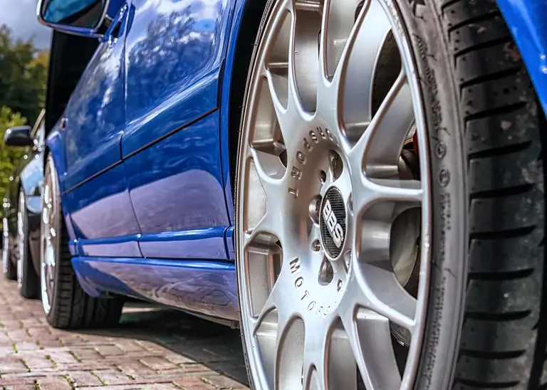Glänzende Leichtmetallfelge an einem gepflegten blauen Fahrzeug